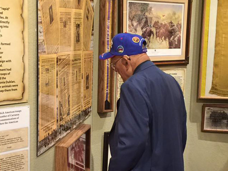 A museum visitor reading a newspaper artifact inside a display.